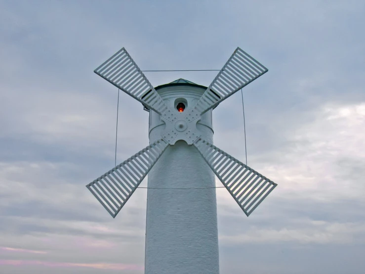 a wind mill sitting above the ocean near water