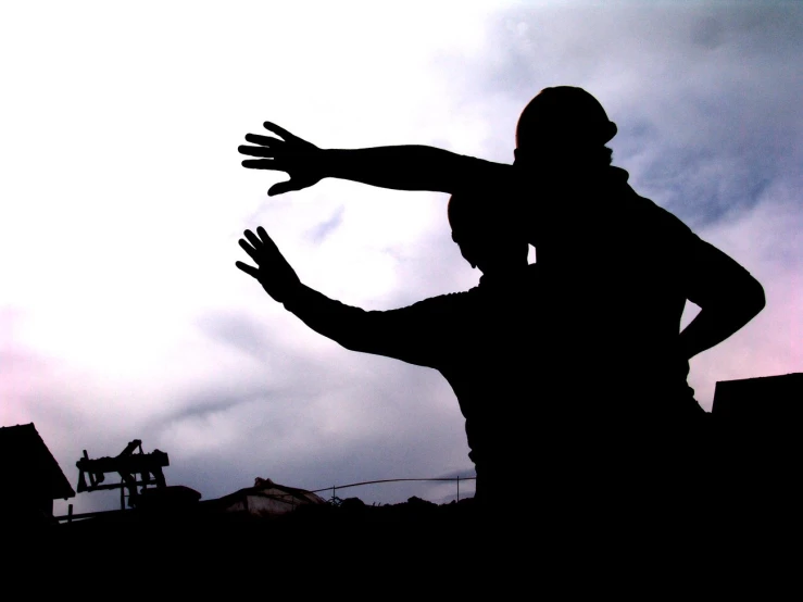 a person is playing frisbee while silhouetted against a cloudy sky