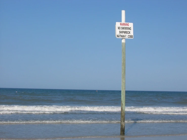 this sign is leaning in front of the ocean