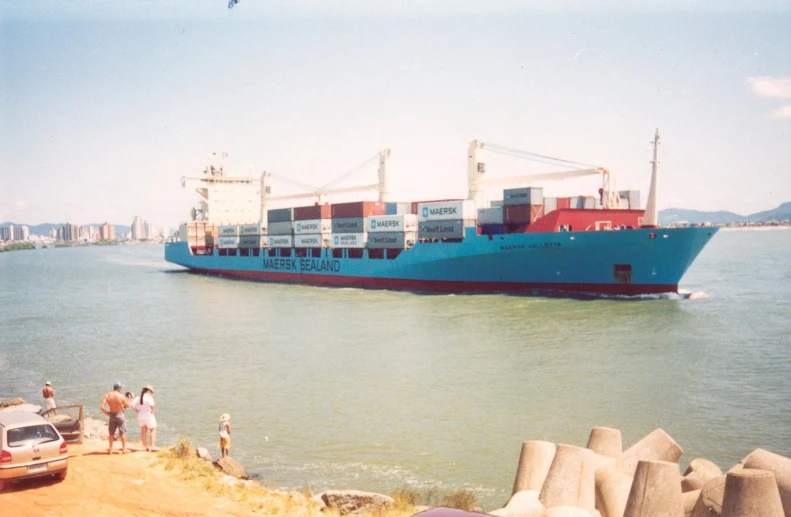 a big blue boat going down a river by the ocean