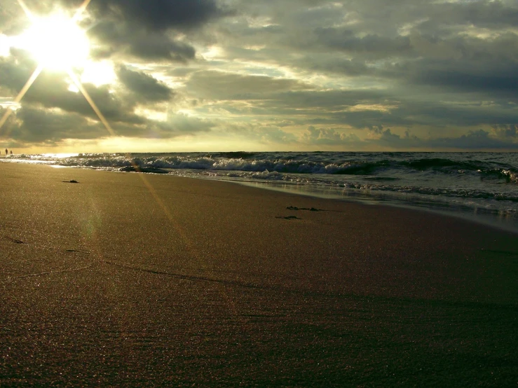 a body of water under a cloudy sky next to the beach