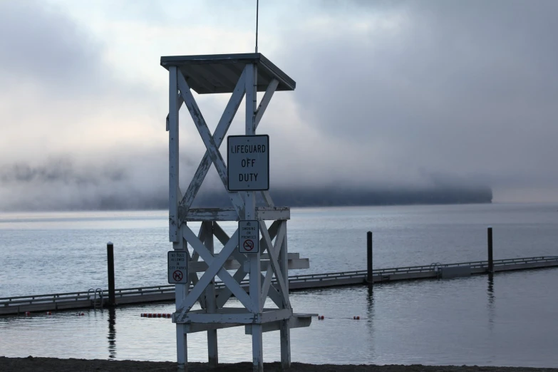 a lifeguard tower stands in front of a body of water