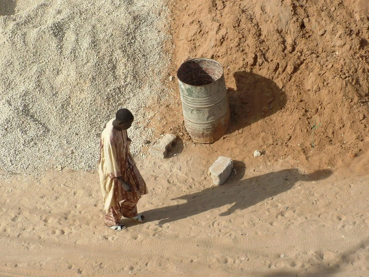 two people walking on sandy ground near a pile of sand