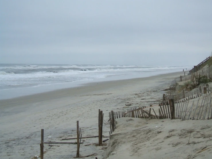 a fence at the edge of the sand near the ocean