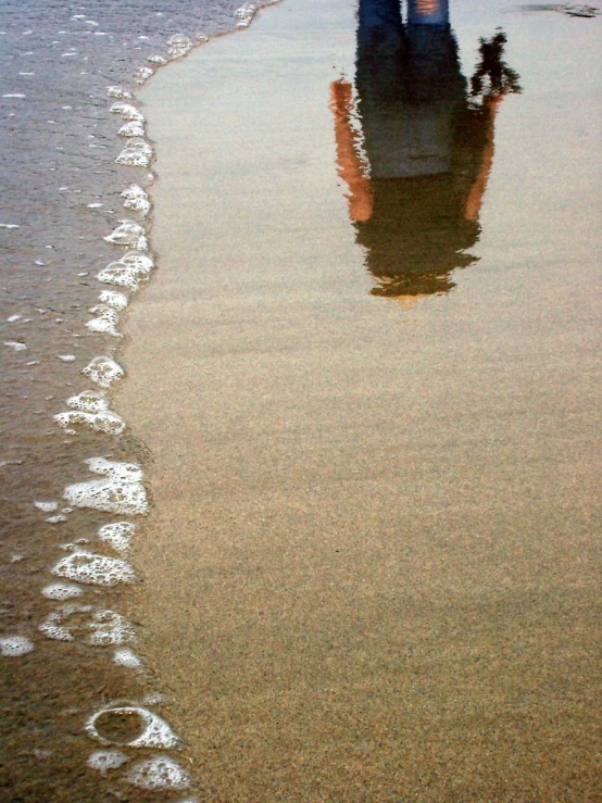 a person stands on the beach as waves lap by them