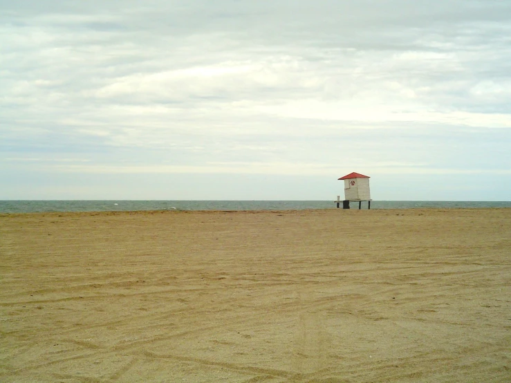 a sandy beach with a red and white life guard tower