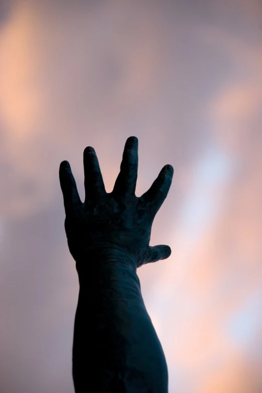 a hand is sticking out from underneath a cloudy sky