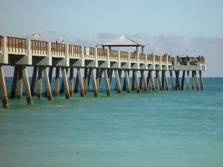 people are walking on the pier over blue water