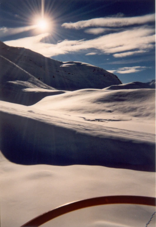 a snow covered landscape with the sun in the sky