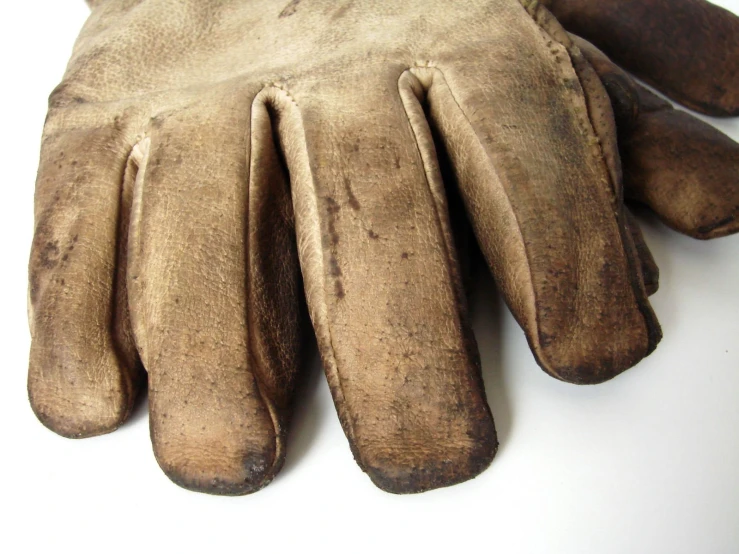 an old glove sits on top of a white surface