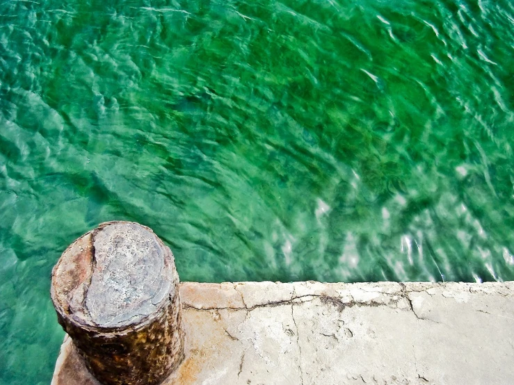 green water is floating through a stone pier