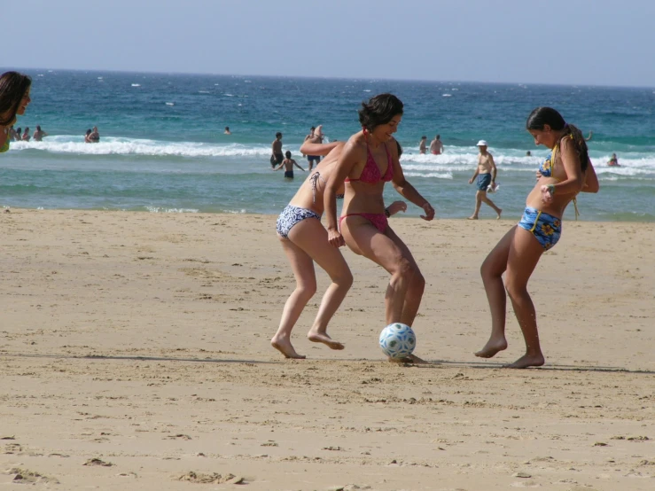 a couple of girls in bikinis play with a ball