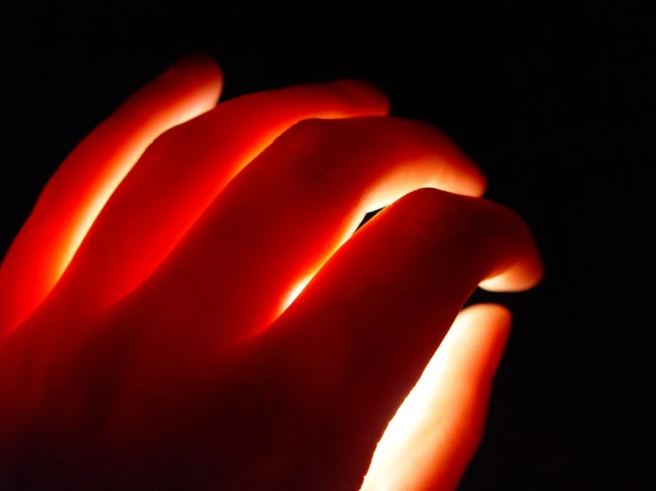 red lighting inside of a plastic hand on a black background