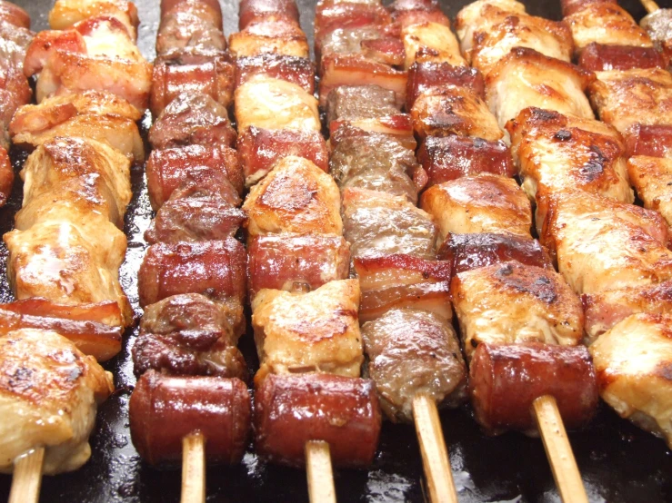 a bunch of chicken skewers sit on a grill