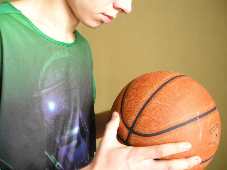 a boy is holding a basketball and looks at the ball