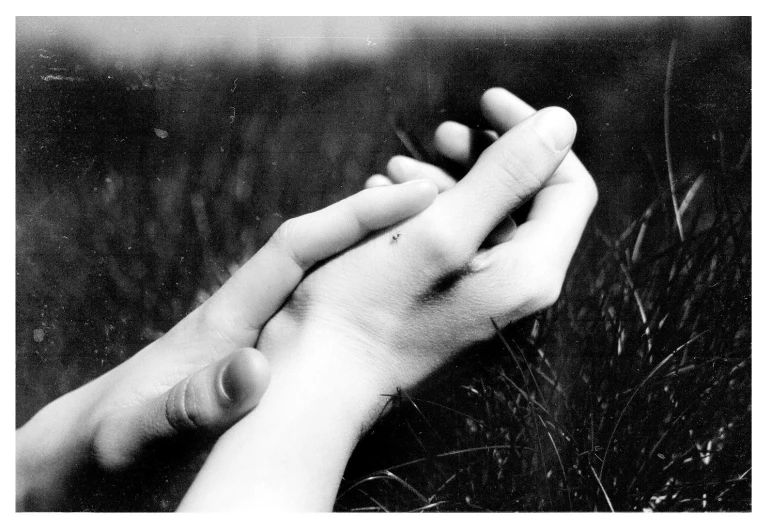 a couple holding hands over each other in a field