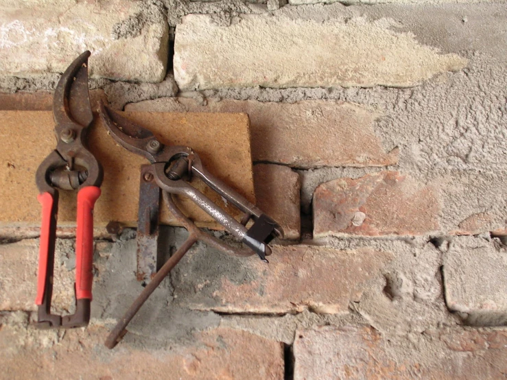 an old rusty wrench on a brick wall next to a small spanner