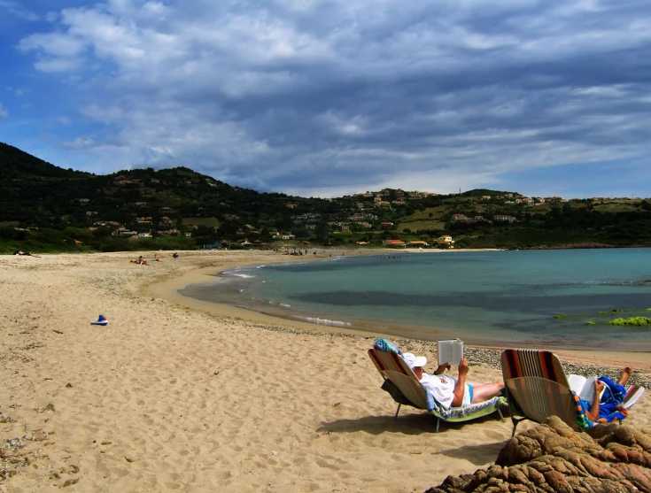 two beach chairs sitting on the shore of a beach