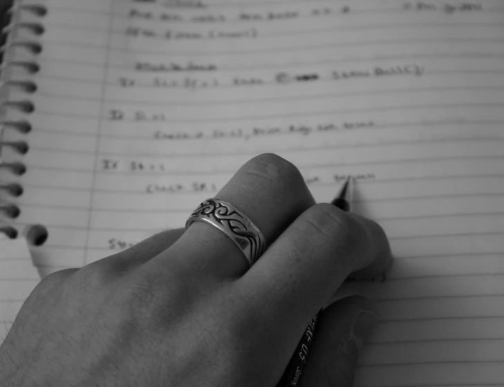 a man is holding on to his ring and writing on lined paper