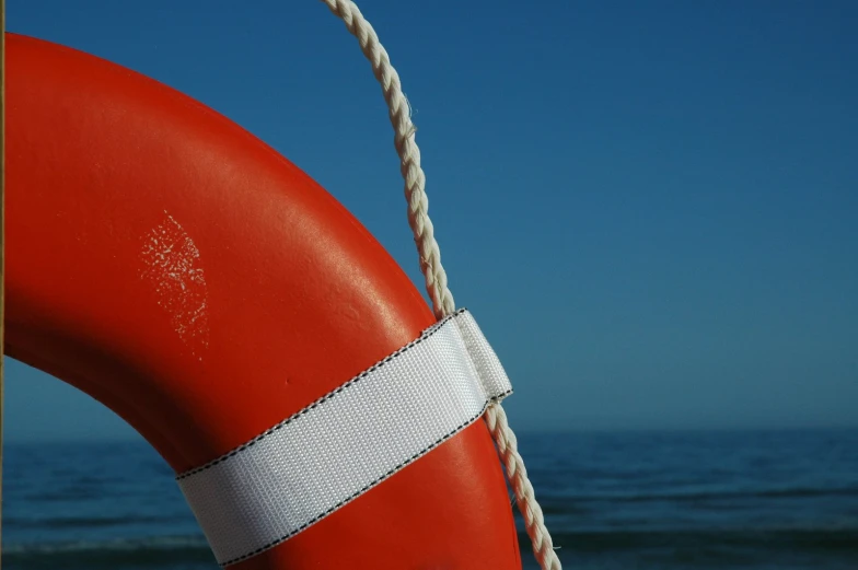 an orange life preserver is in front of the ocean