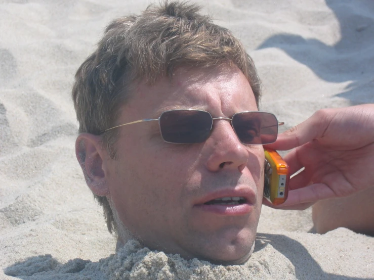 a man with sunglasses that is holding a cell phone