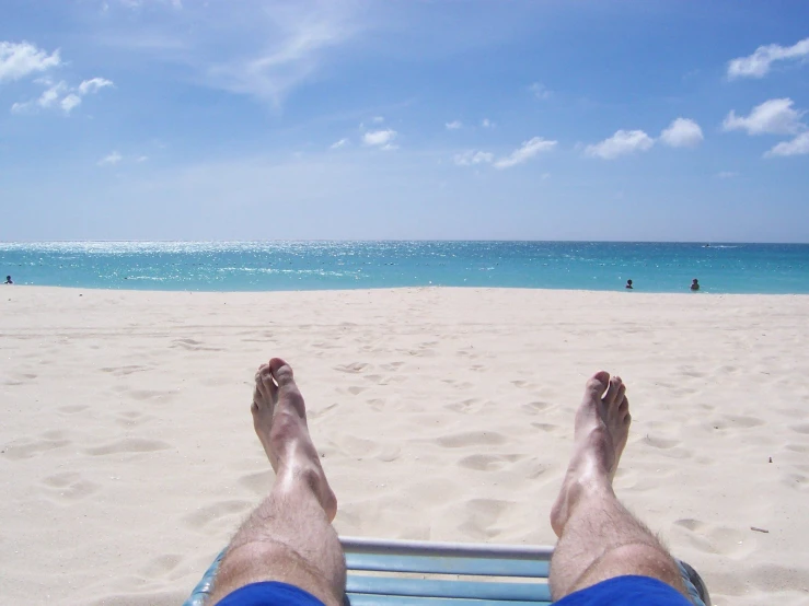 the legs of a man laying on top of a blue bench