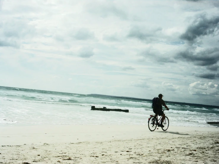 a person riding a bike down a sandy beach