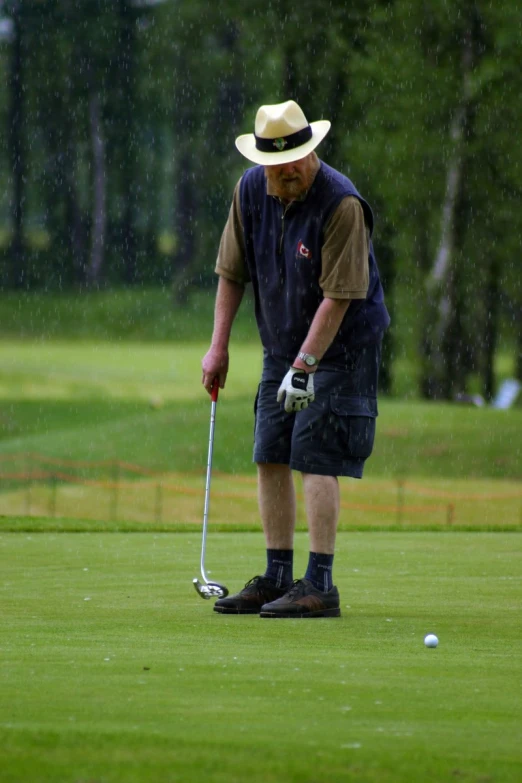 a man standing on top of a green golf field holding a golf club