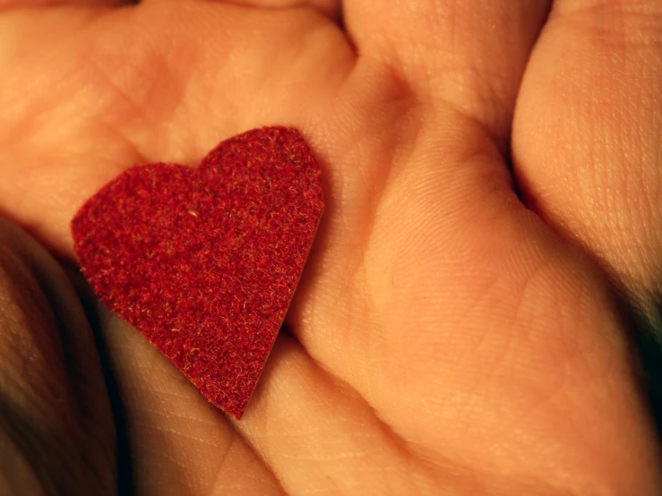 a small red heart placed on a person's hands