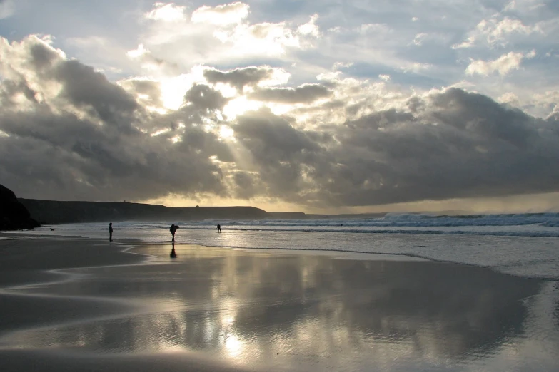 the sun reflects off the water as the two people walk along the beach