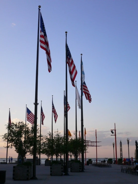 a group of flags in different colors next to a body of water