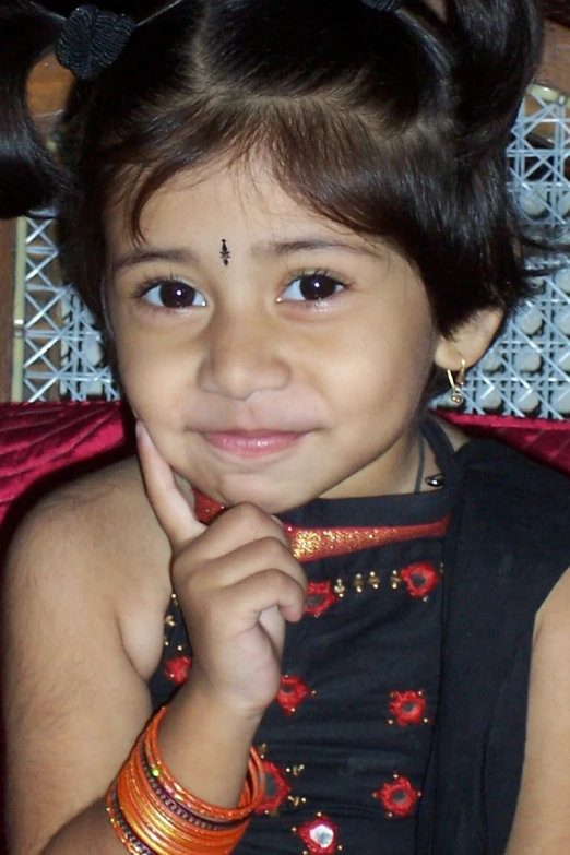 a little girl posing for a po while wearing celets