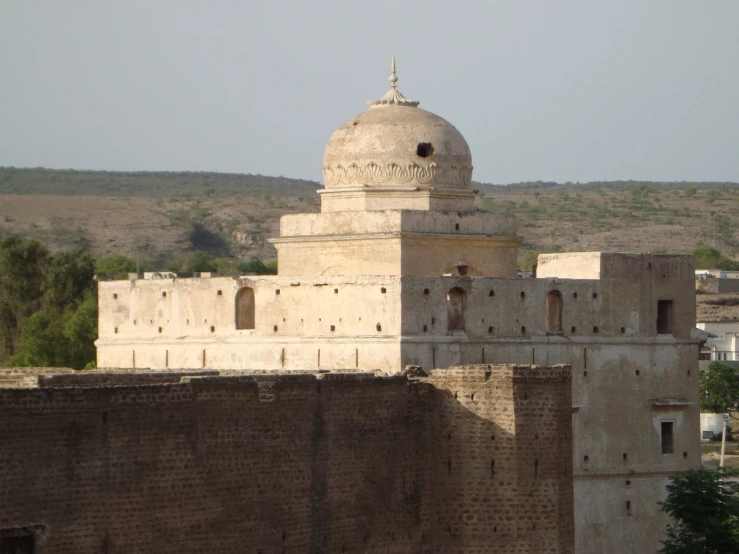 large gray building near wall and trees on top