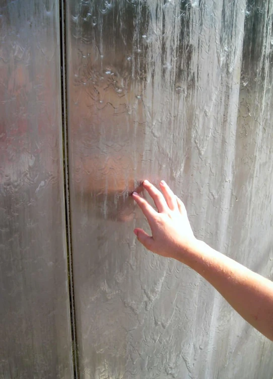 the hand is touching the glass surface of a closed door