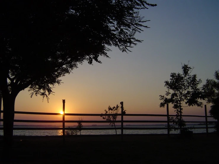 the sun is setting over the ocean as the beach is seen