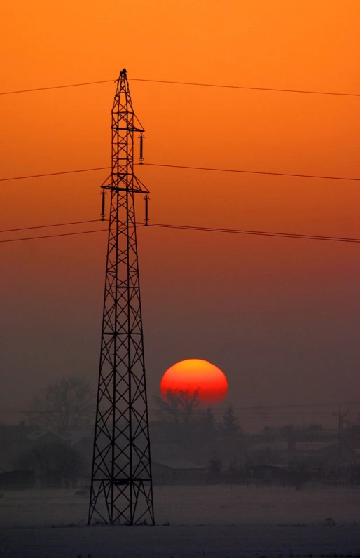 a tall power tower sitting in front of a setting sun