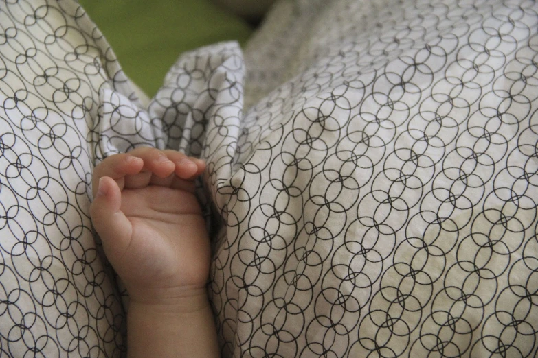 a small hand rests on the cover of a blanket