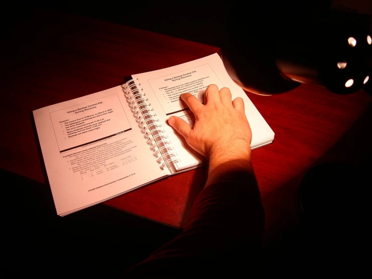 a man is holding a pen as he looks at his notebook