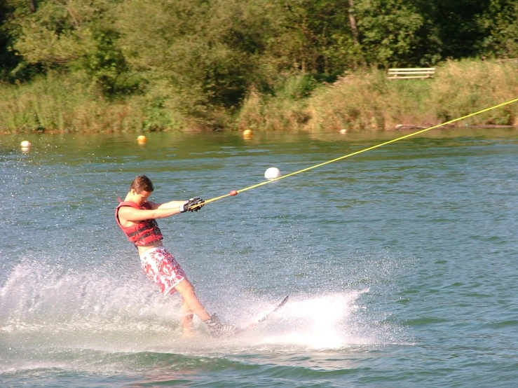 a man riding water skis holding onto a yellow rope