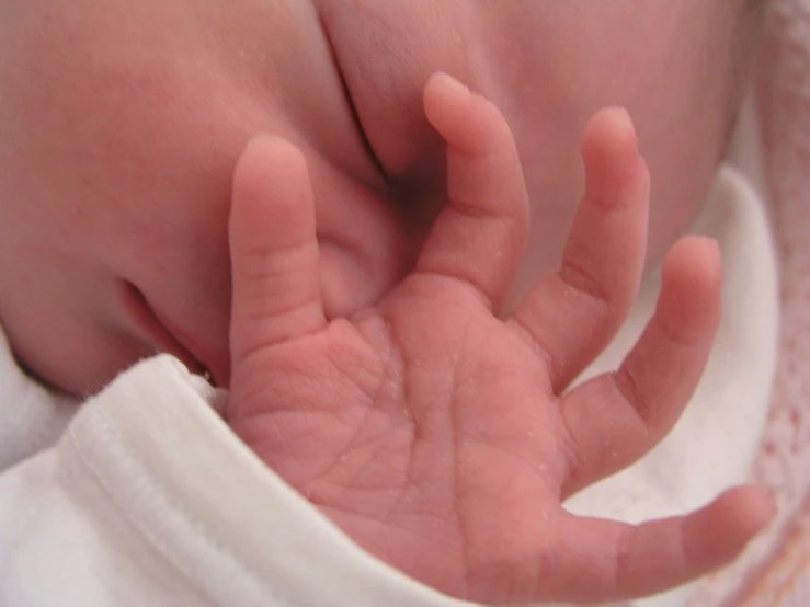 a baby is laying its hands on its chest