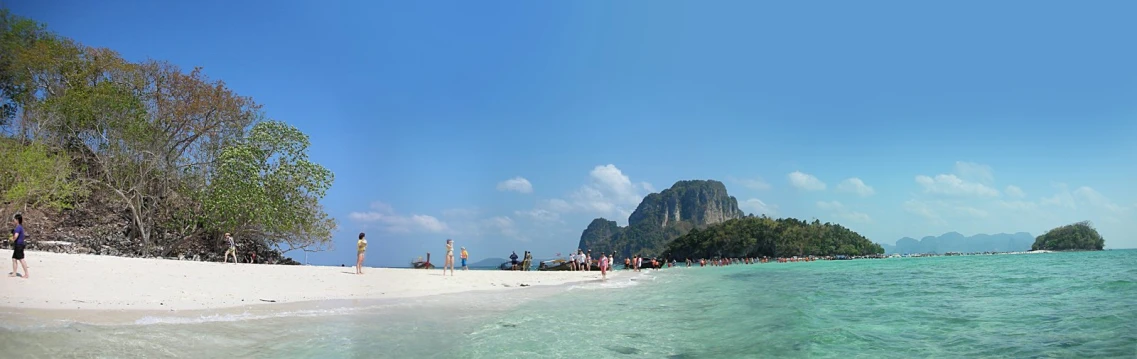 a beach with some people walking in the water