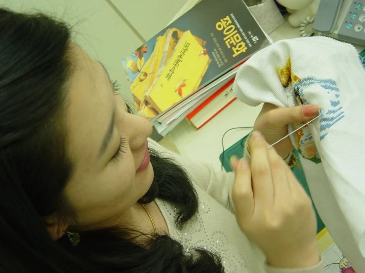 a woman holding a needle in front of a book