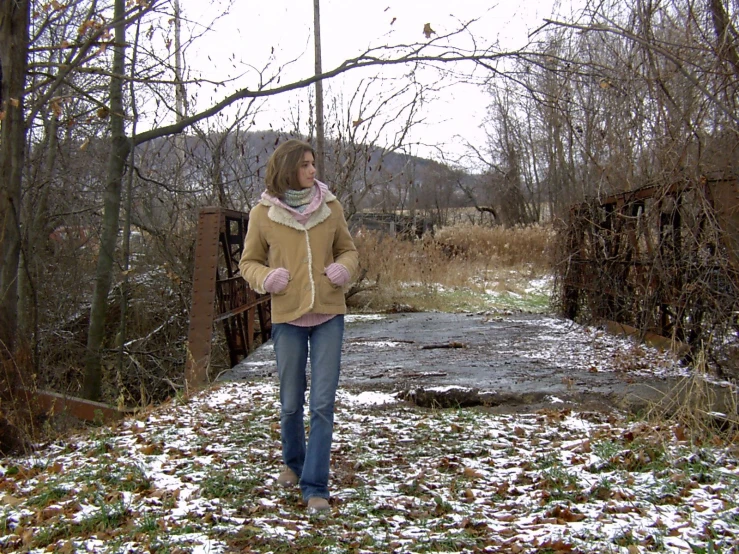 a woman standing in the snow near a bridge