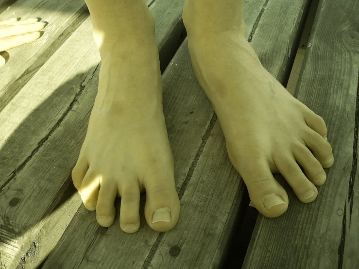 the bare feet of a statue sitting on a wooden bench