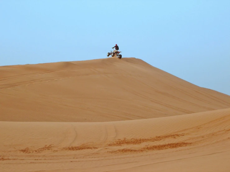 two men riding motorcycles in a wide dune