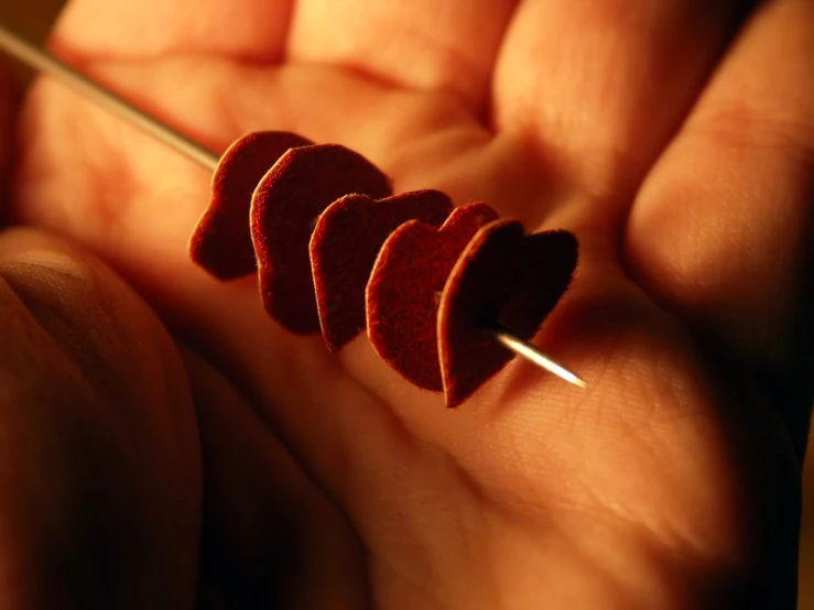 four red hearts are held in the palm of someone's hand