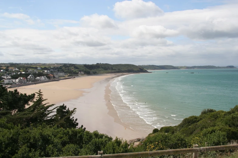 a sandy beach with a fence in the foreground and sea