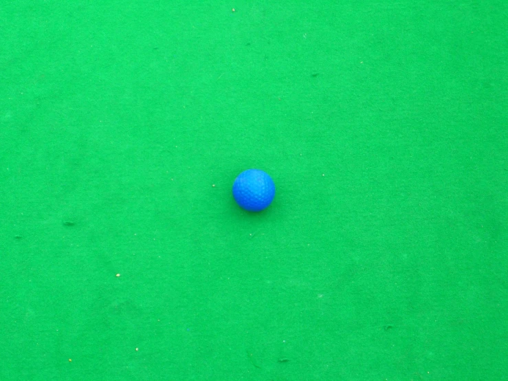 blue ball placed on green surface next to white ball
