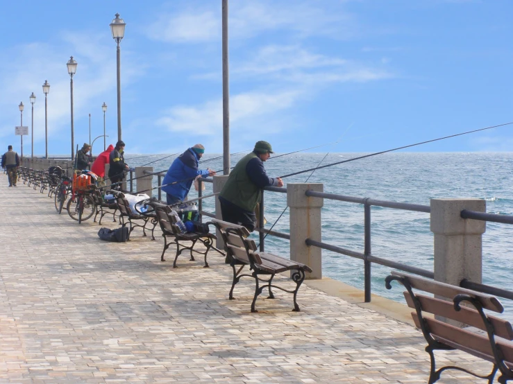 a long pier with people fishing off the benches