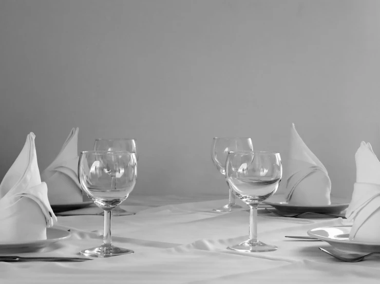 a dining room table set with wine glasses and napkins